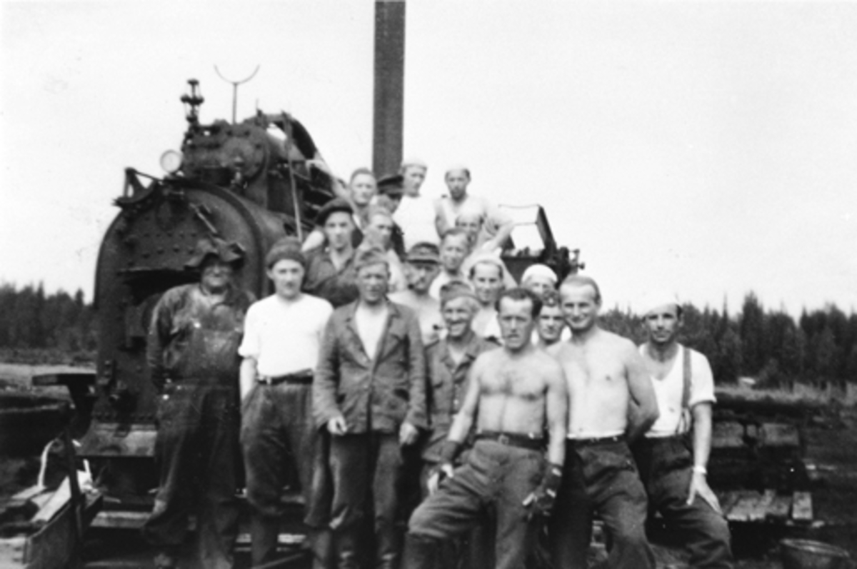 Anno Domkirkeodden, Høljamyra torvfabrikk (Ny-Høljan), Furnes Almenning. Torvdrift i Høljamyra startet i 1934. Gruppe arbeider i torvmyra. Foran lokomobilen er noen tyske krigsfanger. Til venstre er Jørgen Rognlidalen.