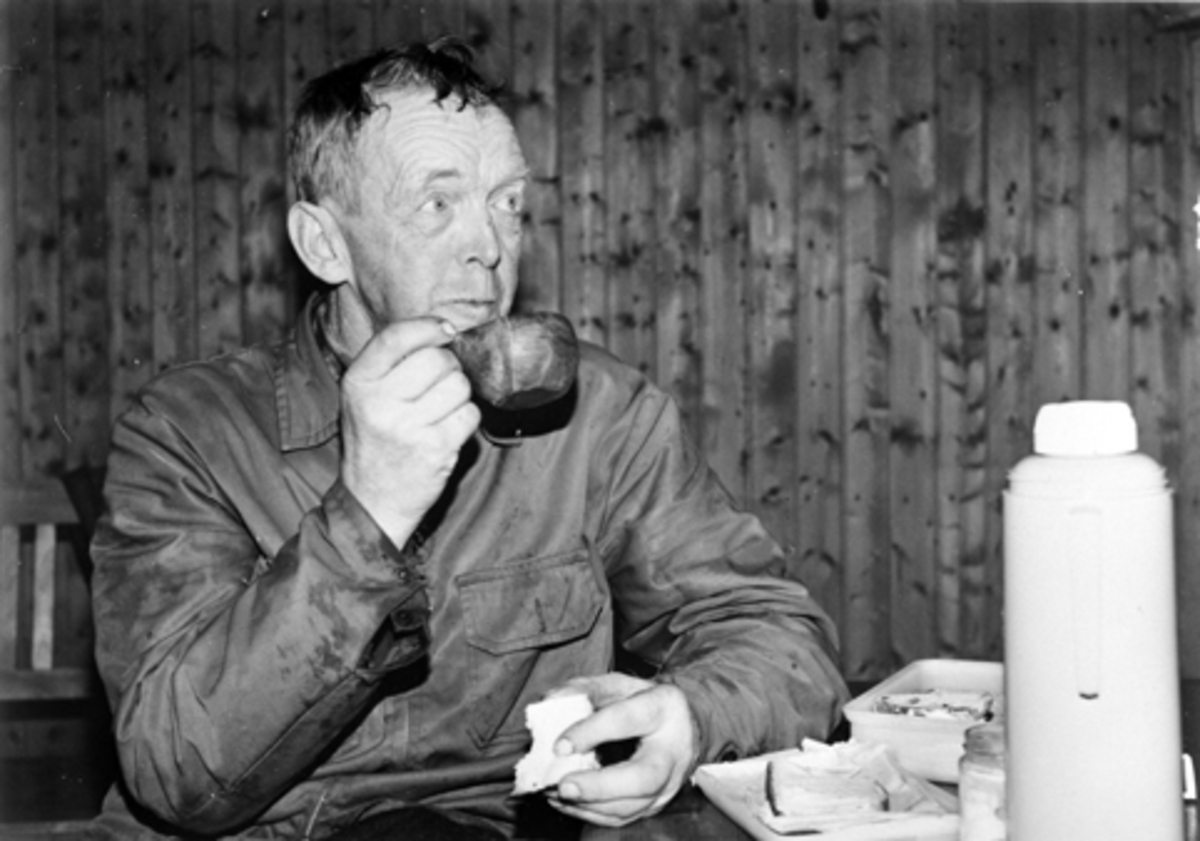 Anno Domkirkeodden, Interiør, Kvemyrkoja. Oskar Lillehovde spiser av nistad si og drikker kaffe fra neverkopp. Furnes Almenning.