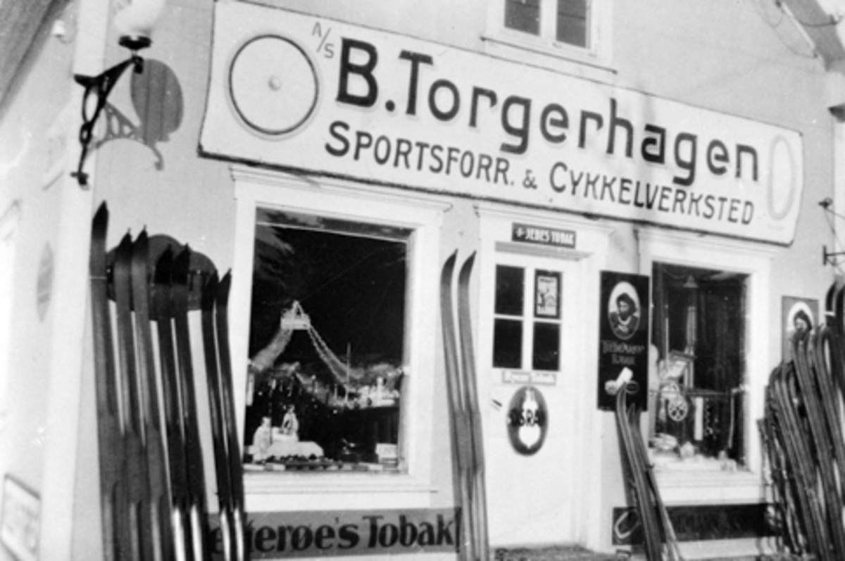 Anno Domkirkeodden, A/S B. Torgerhagen, Sportsforretning & Cykkelverksted. Brumunddal. Ski utstilt utenfor forretningen, reklameplakater "Osram" og "Petterøes tobakk".