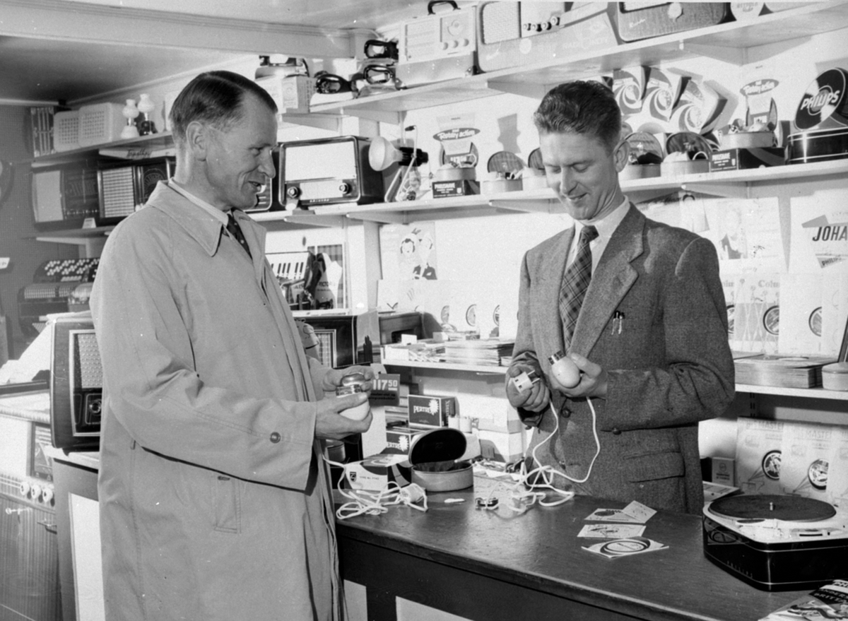 Anno Domkirkeodden, Interiør, Torgerhagen Sportsforretning og Elektrisk forretning. Musikkavdelingen med radioer og grammofon, bak disken er Bjarne Torgerhagen som skal selge barbermaskin til tannlege Hans B. Sæthren.