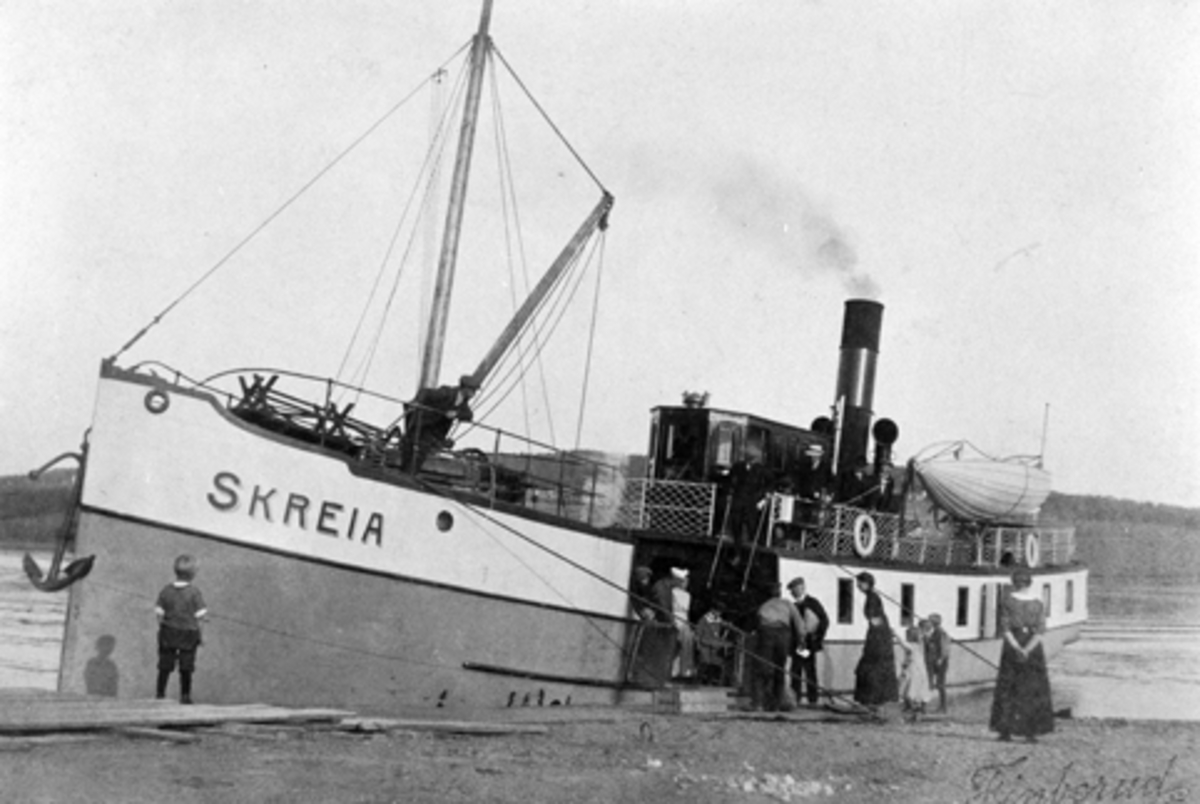Anno Domkirkeodden, Mjøsbåten D.S. Skreia ved Nes brygge på Tingnes. Helgøya i bakgrunnen. Postkort som er stemplet 11.7 1913. Personer i ferd med å går ombord.