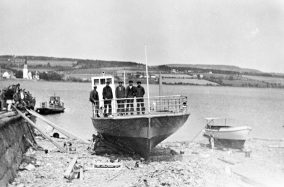 Anno Domkirkeodden, M.F. Helgøya ved Sundsbrygga ved stabelavløpingen den 27.mai 1938. Ferga kunne ta 4 personbiler eller 1 lastebil og 2 personbiler. Ferga var i drift til 1957 da brua over Nessundet ble åpnet. Gamleferga i bakgrunnen.