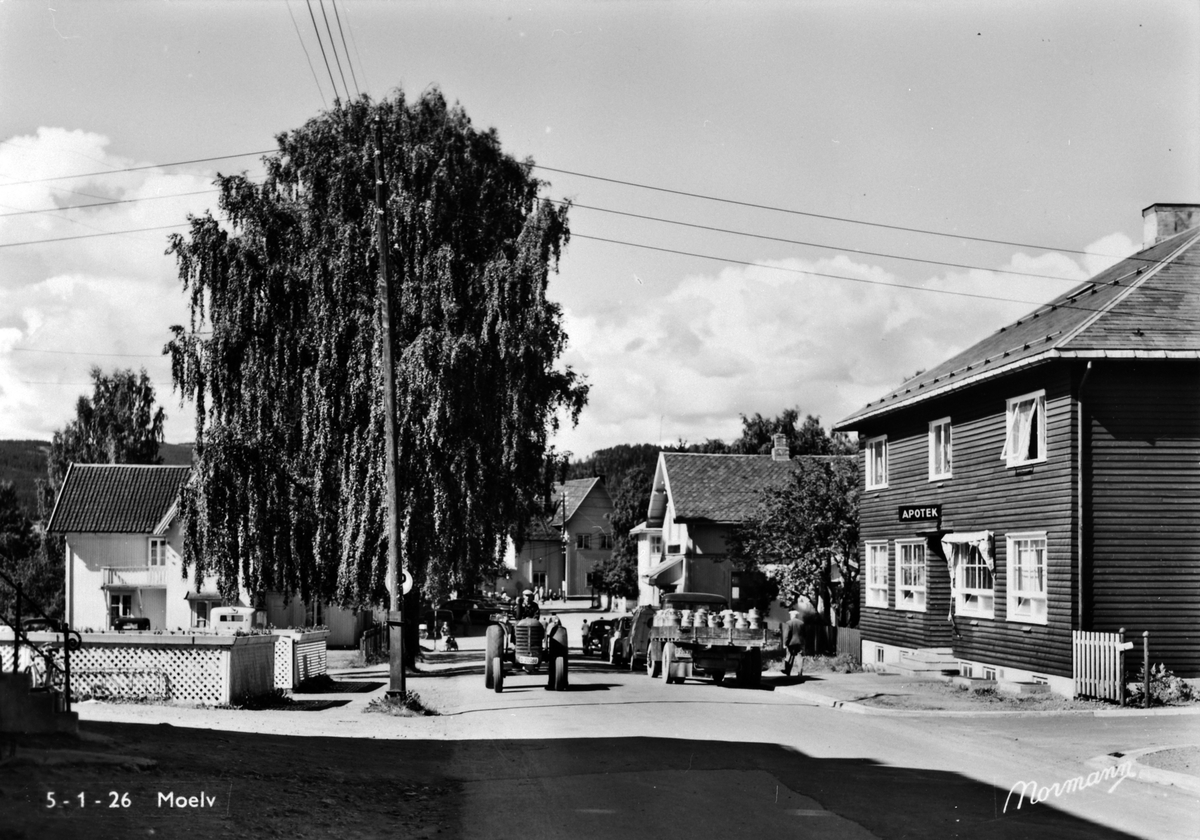 Anno Domkirkeodden, Åsmarkvegen i Moelv, Ringsaker. Traktor, melkebil, 1945-50. Apoteker Sigurd Syvertsen bygget egen apotekergård i Åsmarkvegen 1 i 1941. Huset er tegnet av arkitekt Rolf Prag, Hamar. Huset ble revet i 1976.