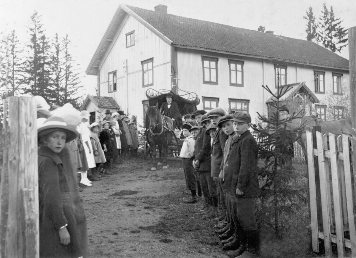 Anno Domkirkeodden, Ukjent sted i Ringsaker. Gravferd. Hest med likvogn kjører ut av gardstunet. Barn og voksne står oppstillt.