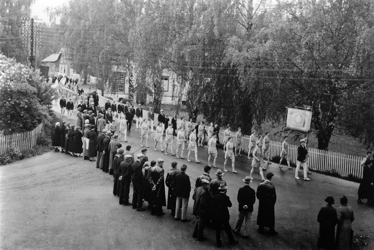 Anno Domkirkeodden, Turnstevne i Moelv, dameturnere med fane passerer Dehlis butikk i Storgata.