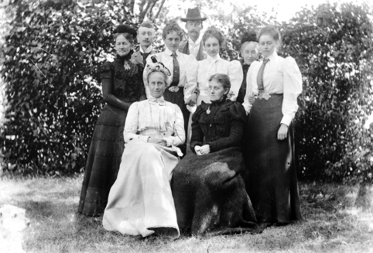 Anno Domkirkeodden, Ni voksne fotografert i hagen på Grefsheim. Sittende fra venstre er Julie Munch Gram og Laura Larsen Naur (F.Munch). Stående er Agnes Petersson (F. Irgens), Mads Gram, Thekla Munch, hoffdame hos dronning Maud, Janken Gram, Lol (Julie) Nissen, f. Mellbye, (1876-1960), Sofie Mellbye (F.Munch), Sofie …