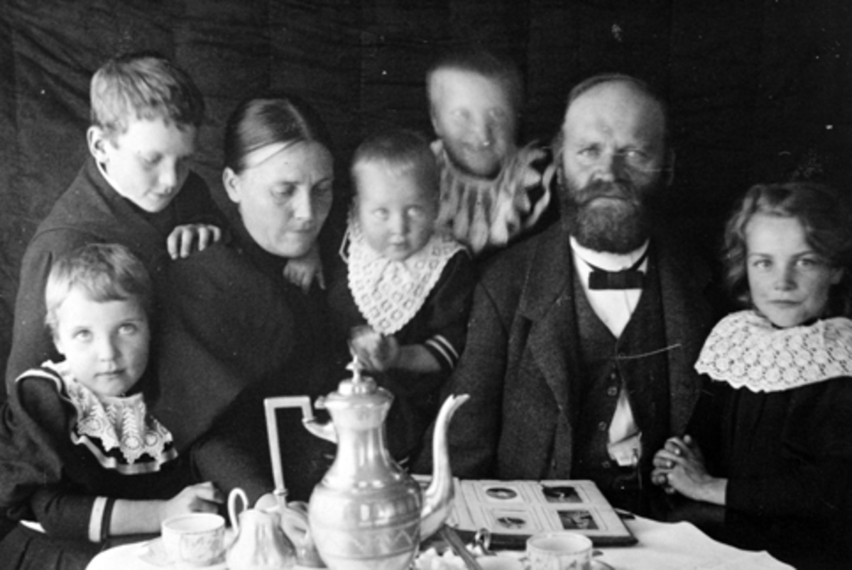 Anno Domkirkeodden, Simenstad gard i Veldre. Bnr. 138-1. Dina og Ansten Simenstad m/ barn. F. v. Dorthea f. 1890, Haaken f. 1886, Kristine f. 1892, Julie f. 1894 og Grethe f. 1888. Kaffebord, kanne, familien ser i fotoalbum. Ca. 1896.
