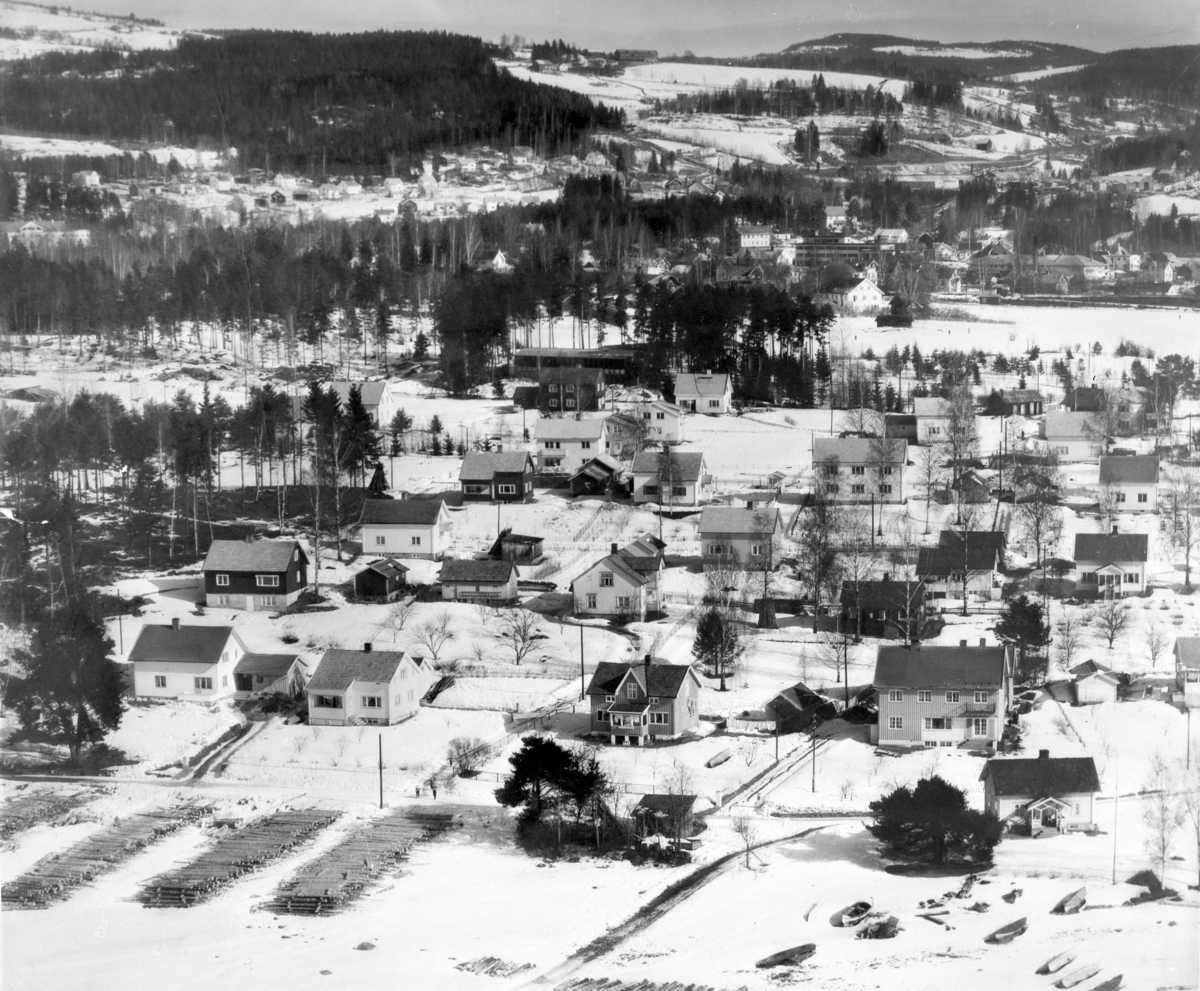 Anno Domkirkeodden, Flyfoto, Moelv. Bebyggelsen ved Moelv Brygge og Strandvegen, Moelv Realskole. Tømmer lagret i Strandkanten.