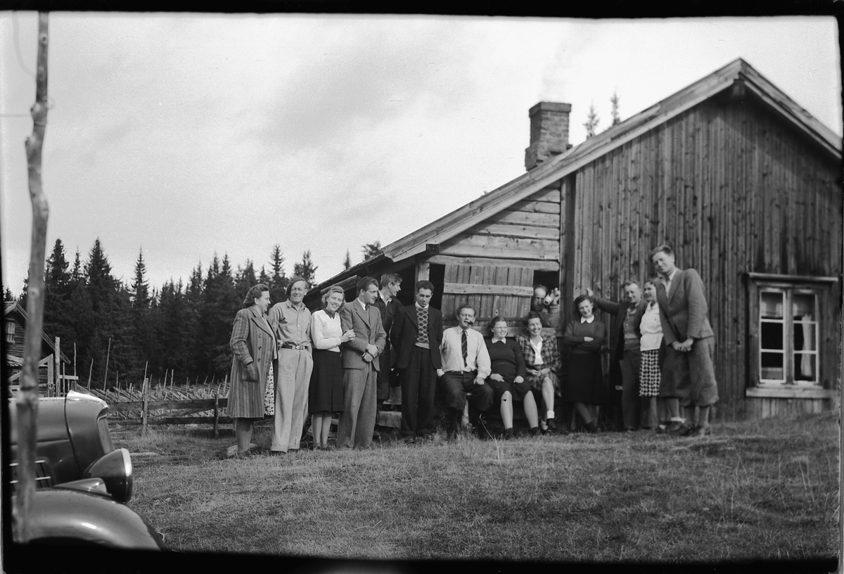 Håkon Prestkværn, Gruppe personer foran ei hytte. Fra venstre fru Eriksen, Mikael Eriksen, Hjørdis og Kåre Tranget, Arne Vea, Johs. Nordhagen, Lars R. Haugen, ukjent, Ingeborg Haugen, ukjent, ? Tranget, ? Pedersen og frue, ukjent. Betjeningnen på Moelven meieri på tur.
