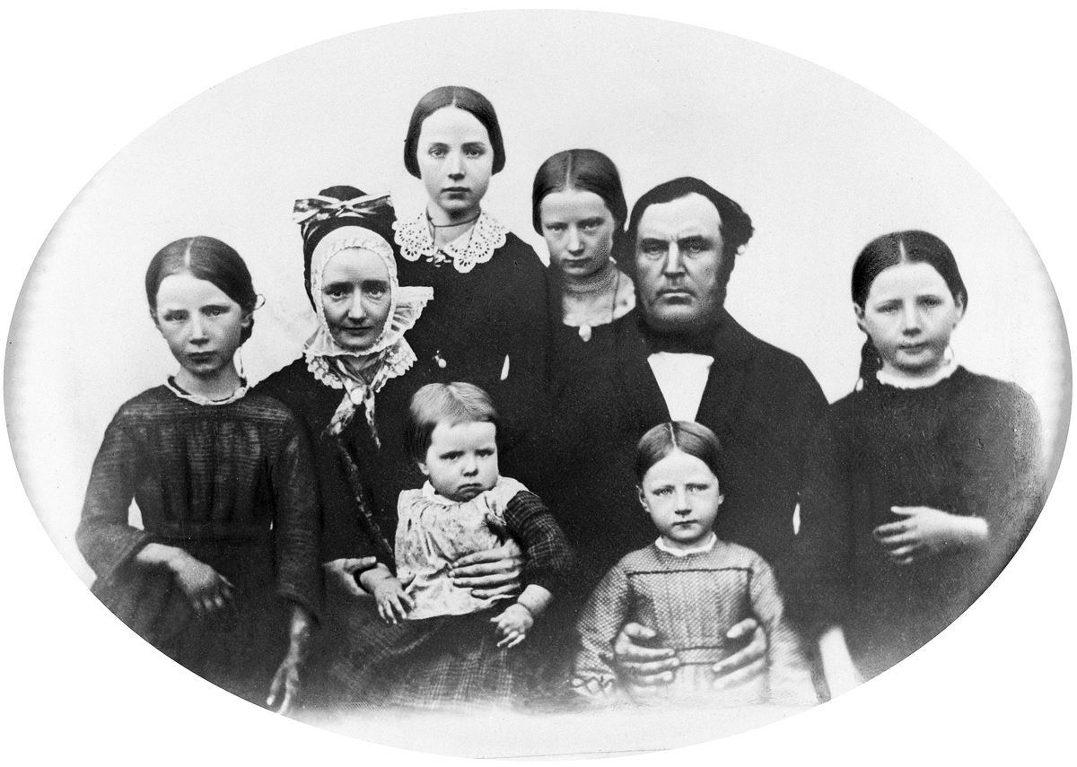 Anno Domkirkeodden, Gruppe 8 familien Johan Gjestvang, foran fra venstre: Julie og Johanne, bak fra venstre: Oline, Andrea, Gina Matea, Ingeborg, Johan og Karoline. Andrea Gjestvang, f. 1820 med høg rynkelue og tettsittende skrud.