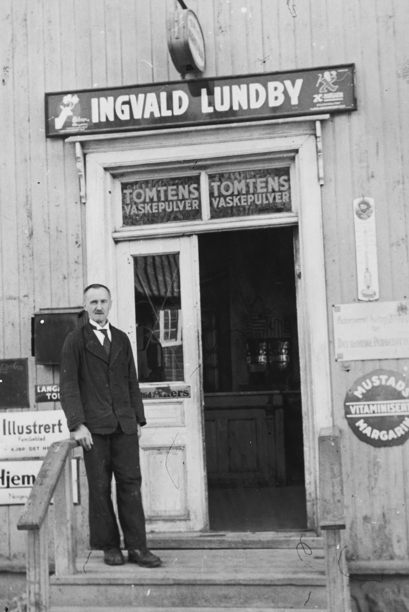 Ukjent, Landhandler Ingvald O. Lundby på trappa utenfor butikken ved Vik på Tangen i 1930-årene. 166-33. Reklameskilt. Flere opplysninger se boka "Handelssteder i Stange" skrevet av Jan Arne Berg, utgitt av Stange Historielag 2012