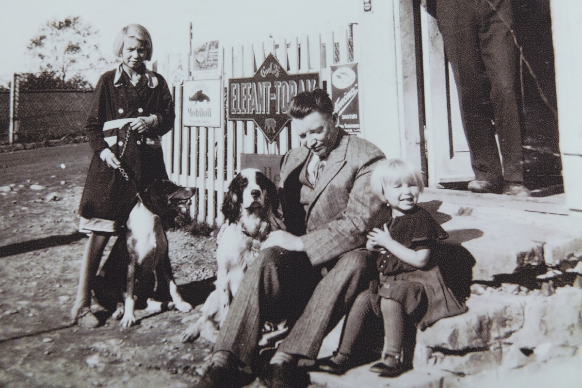 Ukjent, Kjøpmann O. Holm på trappa foran den gamle landhandlerbutiken på Espa i 1935 sammen med døtrene f. v. Ellen Johanne Holm og Astrid Holm Flere opplysninger se boka "Handelssteder i Stange" skrevet av Jan Arne Berg, utgitt av Stange Historielag 2012