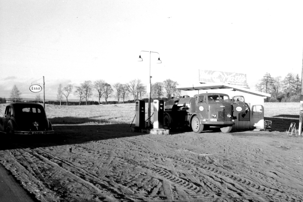 Ukjent, Rolf A. Olsen Landhandel, ca 1965-1970. Reklame, riksveg 50, Stange. Skjelvenga G. nr. 58-2. Esso bensinstasjon, bensinbil. Commer tankbil. Flere opplysninger se boka "Handelsforretninger i Stangeby`n med omegn" skrevet av Jan Arne Berg, utgitt av Stange Historielag 2013.