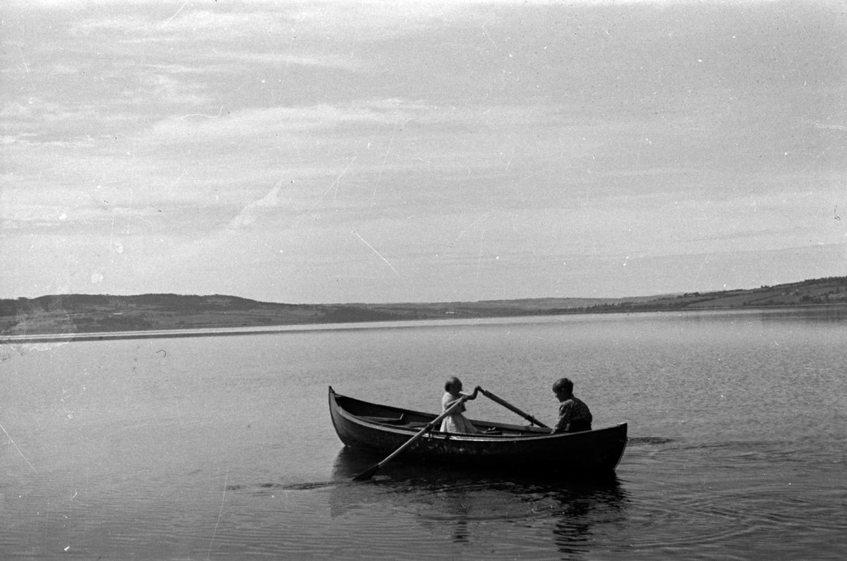 Adolf Skjegstad, Ved Skjegstad-hytta på Furubergstranda, Strandvegen langs Mjøsa i Hamar. Barn i robåt,, mjøsbåt. Med Helgøya, Nessundet og Nes-landet i bakgrunnen.