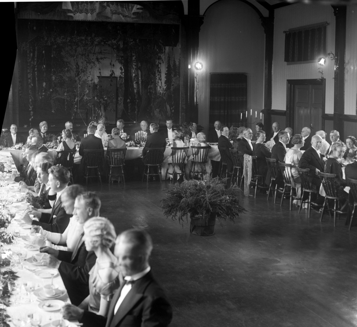 Christian Grundseth, LUNDBY, BRYLLUP, MIDDAGSSELSKAP, LANGBORD 38033 Dette bildet fra Framheim i oktober 1934 gjelder bryllupet til Anstein Erling, kalt AE, Dobloug og Gerd Lundby. Til høyre for brudepartet sitter fra høyre onkel Knut Lundby og mor Berthe Dobloug, og til venstre for brudeparet sitter fra høyre dyrlege …
