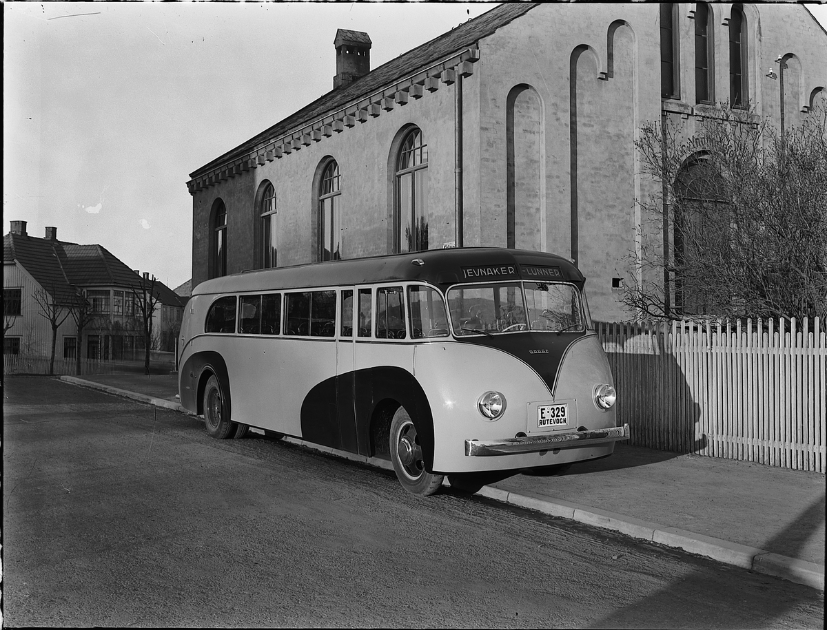 Christian Grundseth, BUSS, DODGE 1938 MED FOLDETAK. E-329. CHASSISET LEVERT AV OLRUD AUTO, OMBYGD TIL HEKKMOTOR OG PÅBYGD KAROSSERIET AV BRUMUNDDAL MEK. VERKSTED & STØPERI FOR RUTEBILEIER JOHAN ANDERSEN, JEVNAKER (JEVNAKER BILRUTER). BUSSEN BLE ØDELAGT UNDER KAMPENE I APRIL 1940. FOTOGRAFERT FORAN YNGLINGEN I KIRKEGATA…