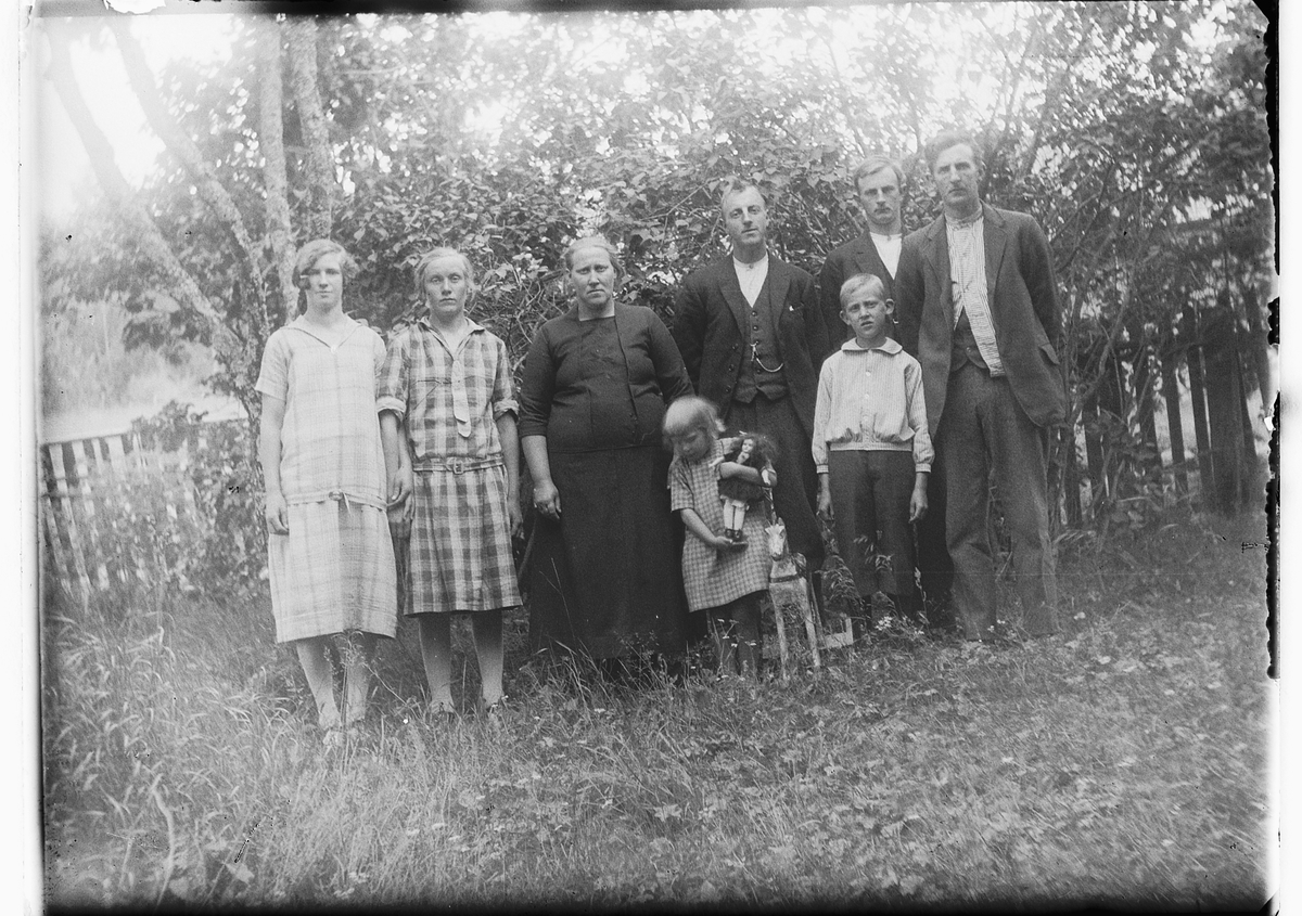 Ole M Martinsen, Ukjent gruppe, familie i en hage. Jente med dokke og gyngehest.