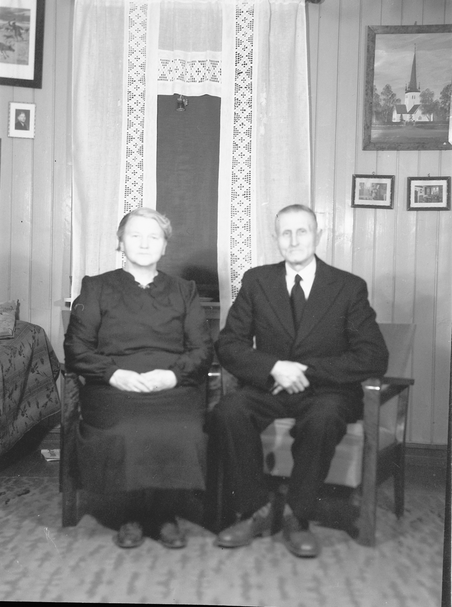 Håkon Prestkværn, Nilsveen, eldre ektepar i stue, interiør.