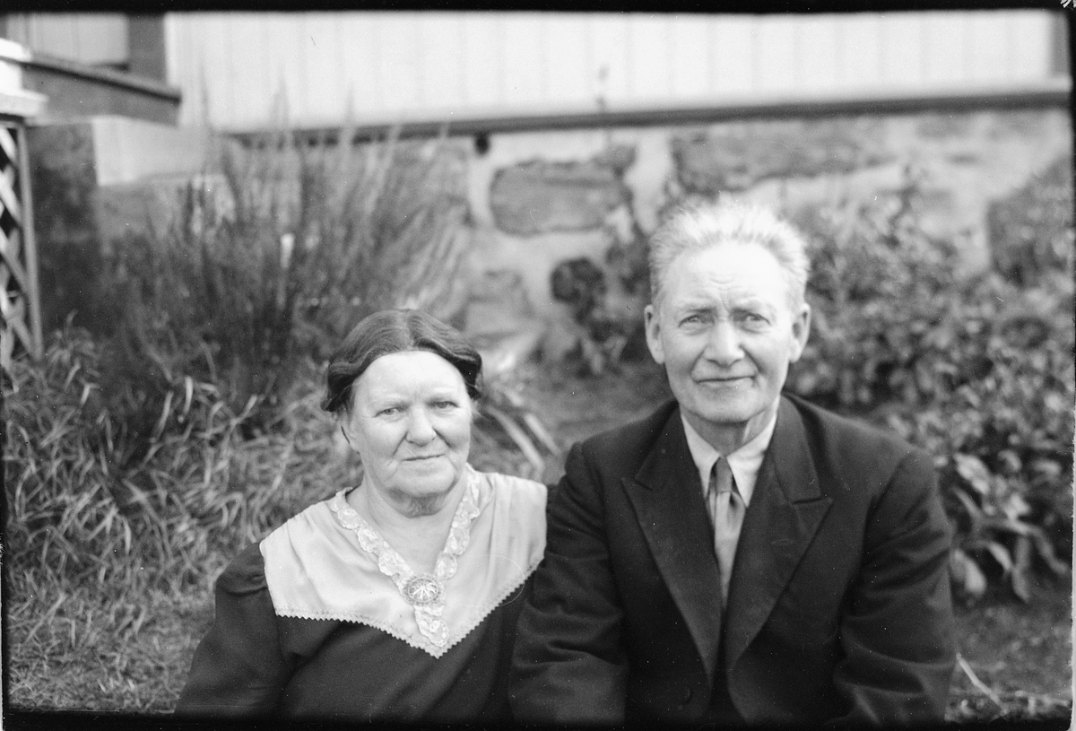 Håkon Prestkværn, Eldre kvinne og mann ved husveggen.