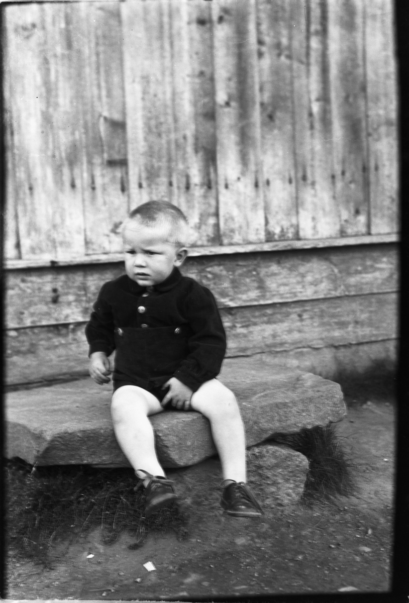Håkon Prestkværn, Liten gutt sitter på en steinhelle.