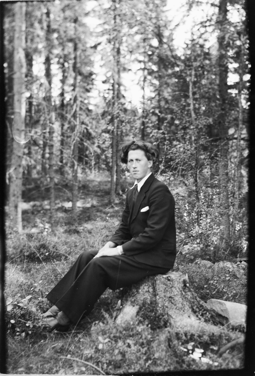 Håkon Prestkværn, Ukjent mann i dress på en stubbe i skogen.