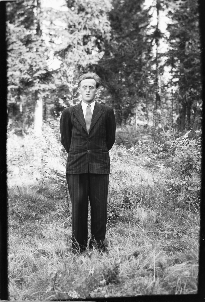 Håkon Prestkværn, Mann i dress i skogen.