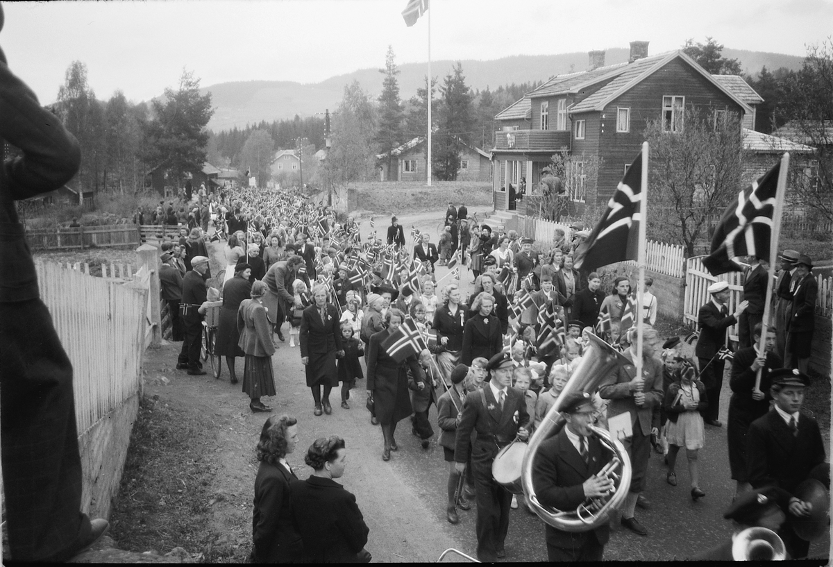 Håkon Prestkværn, Stor gruppe mennesker går i tog med faner og norske flagg. Fremst går musikkorpset. Moelv ved Fønix.