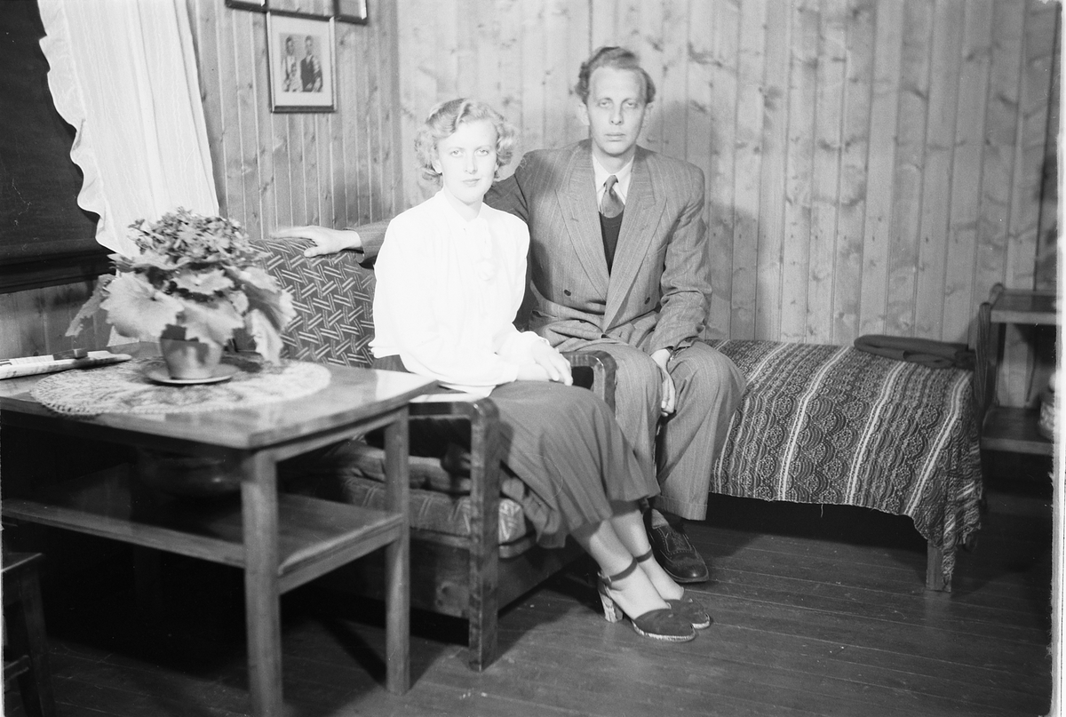 Håkon Prestkværn, Interiør, stue. Ukjent kvinne i stol og en mann i sofaen.