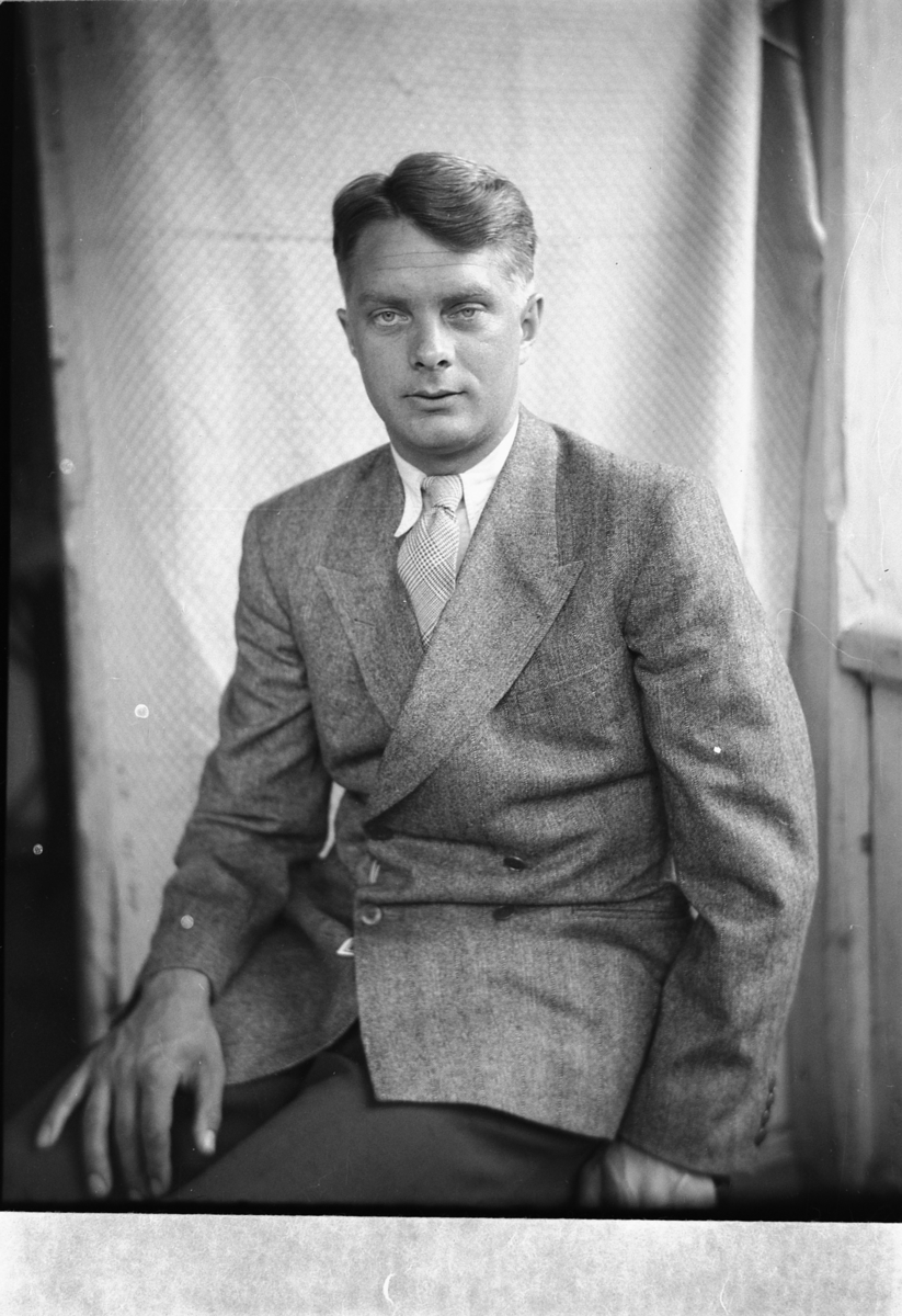 Håkon Prestkværn, Ukjent mann med dress i en stol på trammen.