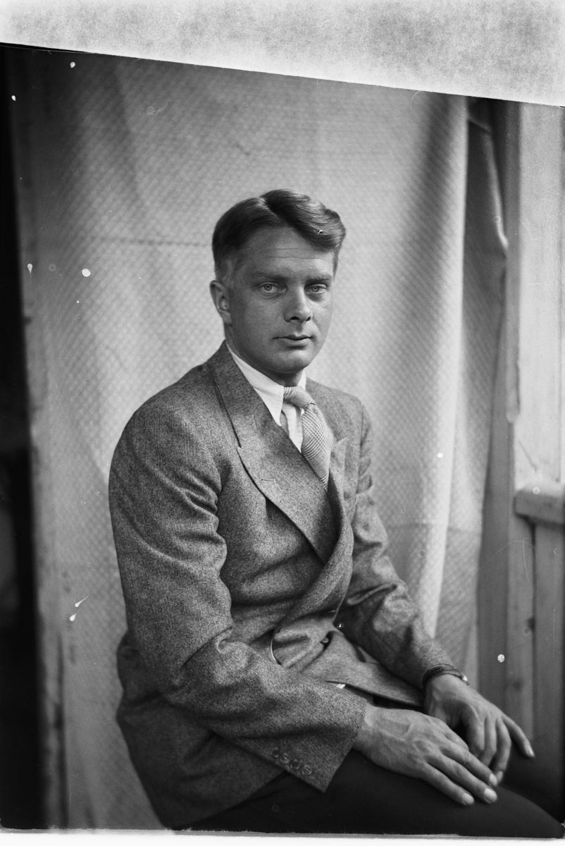 Håkon Prestkværn, Ukjent mann med dress i en stol på trammen.