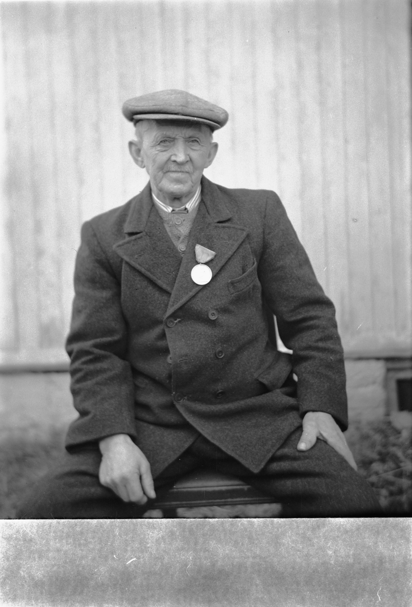 Håkon Prestkværn, Eldre mann med sixpence og medalje på jakkekragen.