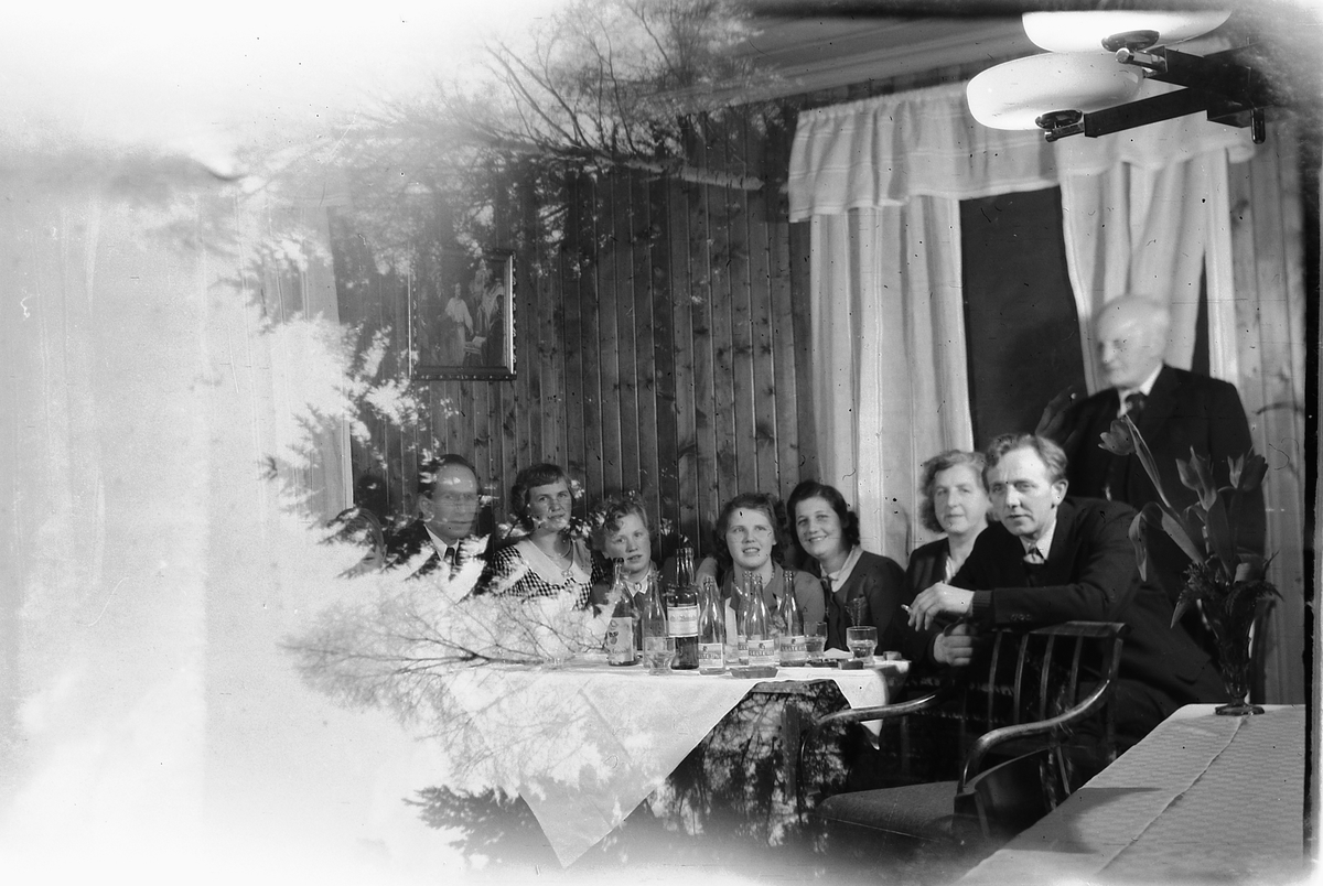 Håkon Prestkværn, Interiør, stue. Ukjent familiegruppe samlet rundt et bord.
