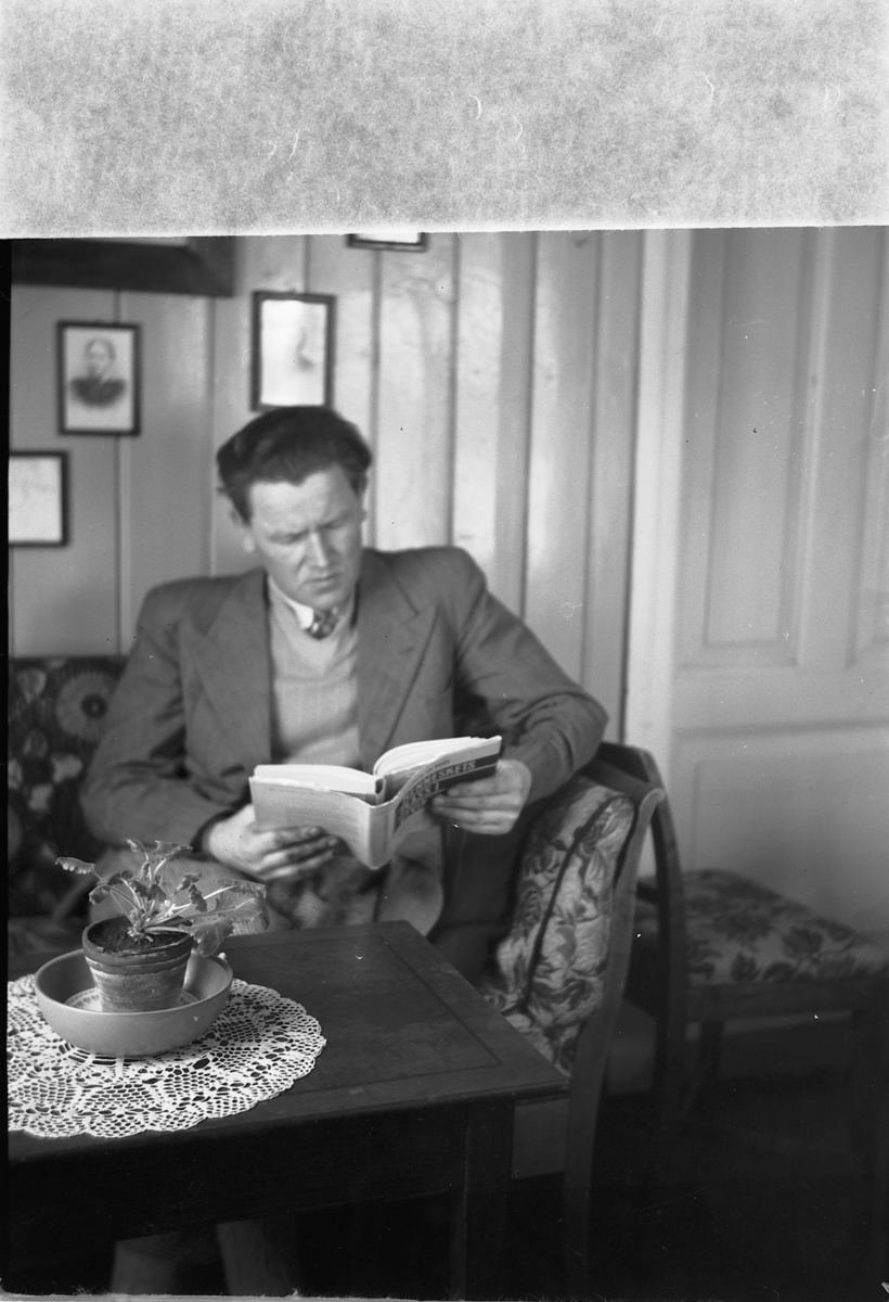 Håkon Prestkværn, Interiør, stue. Mann leser i sofaen.