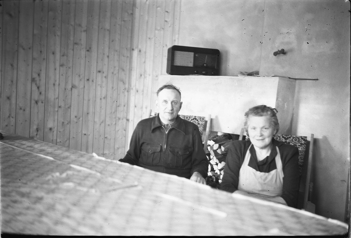 Håkon Prestkværn, Eldre mann og kvinne med en radio i bakgrunnen.