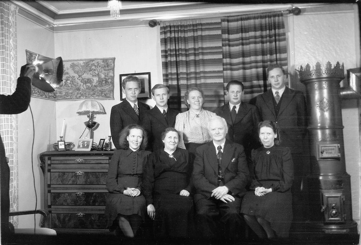 Håkon Prestkværn, Interiør, stue med ovn. Ukjent familiegruppe.