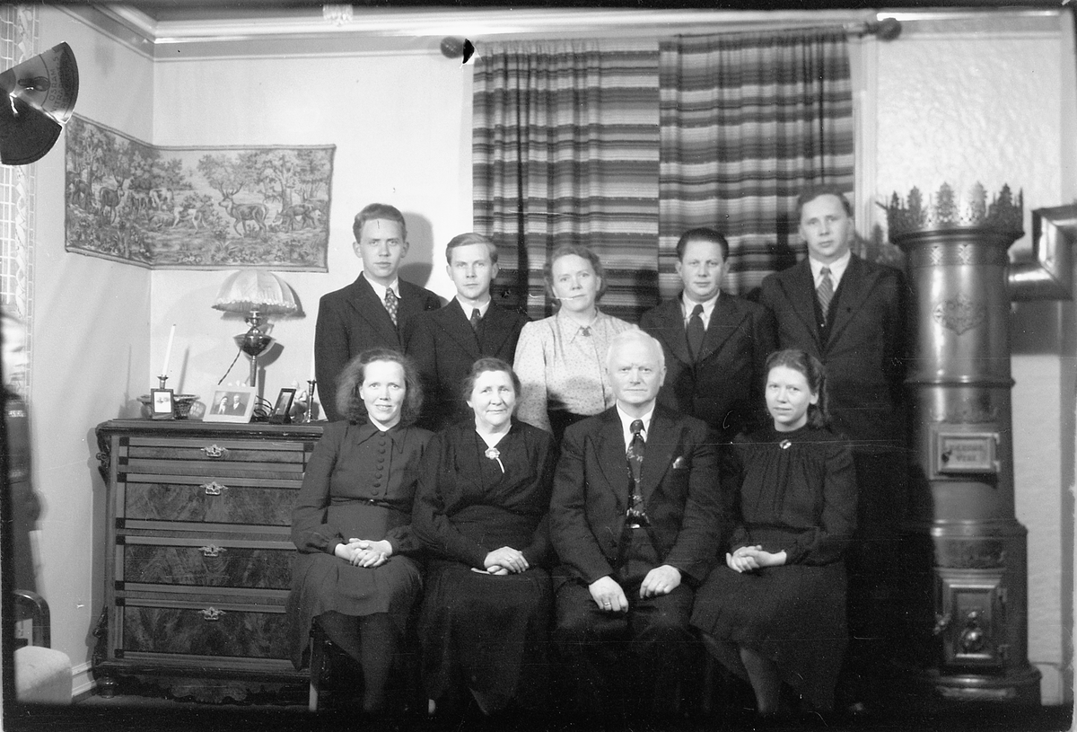 Håkon Prestkværn, Interiør, stue med ovn. Ukjent familiegruppe.