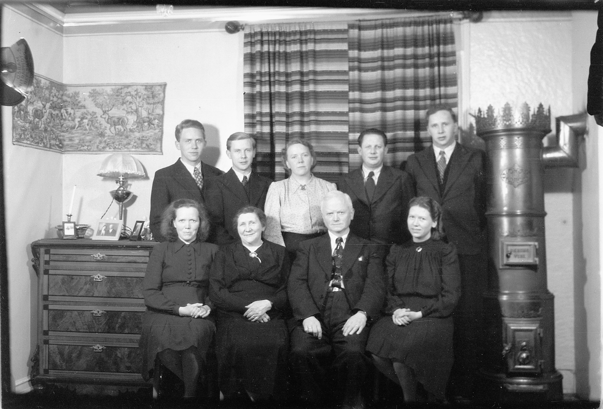 Håkon Prestkværn, Interiør, stue med ovn. Ukjent familiegruppe.