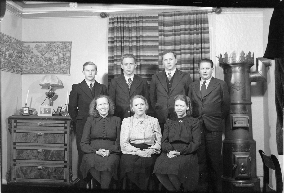 Håkon Prestkværn, Interiør, stue med ovn. Ukjent familiegruppe.
