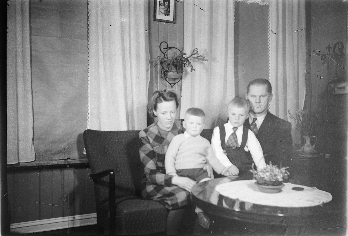Håkon Prestkværn, Interiør, stue. Ukjen familie i sofaen.