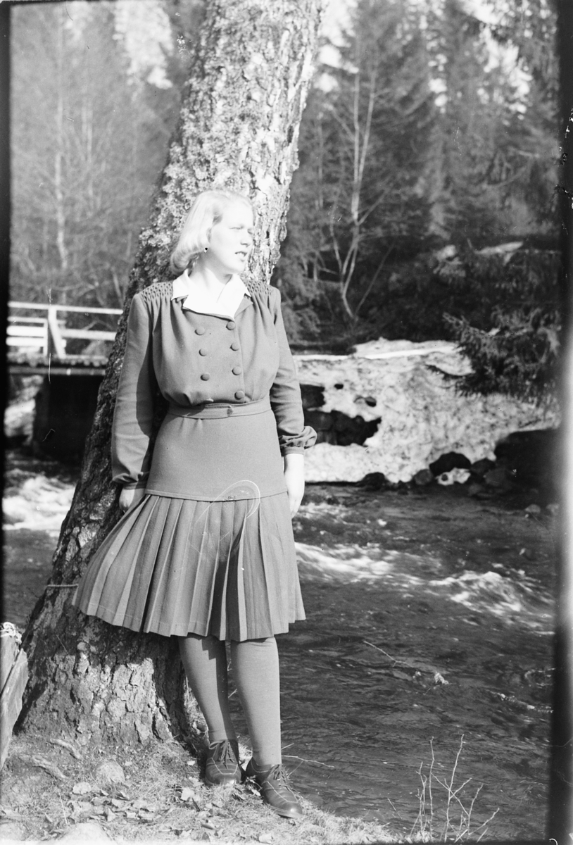 Håkon Prestkværn, Ukjent kvinne står inntil et tre ved ei elv. Fotokonvolutt mrk. "Frknr. Hagen slutten april 1948"