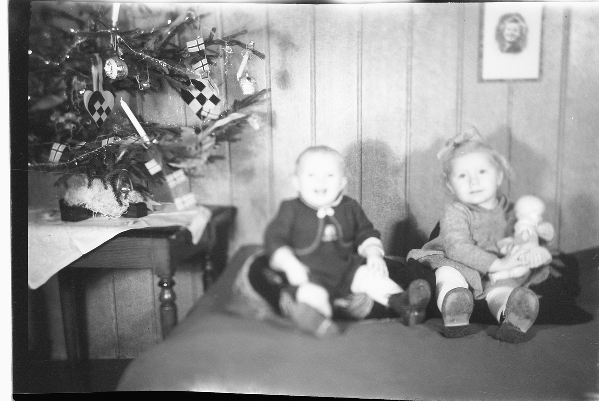 Håkon Prestkværn, Interiør, stue med juletre. To babyer med en dokke sitter i en sofa. "fotokonvolutt mrk. Aaseth julen 1948"