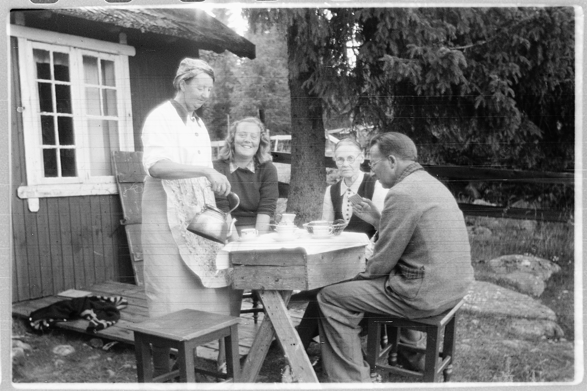 Håkon Prestkværn, Gruppe mennesker drikker kaffe på trammen til ei hytte. nr. 3 f. v. Gunda Prestkværn