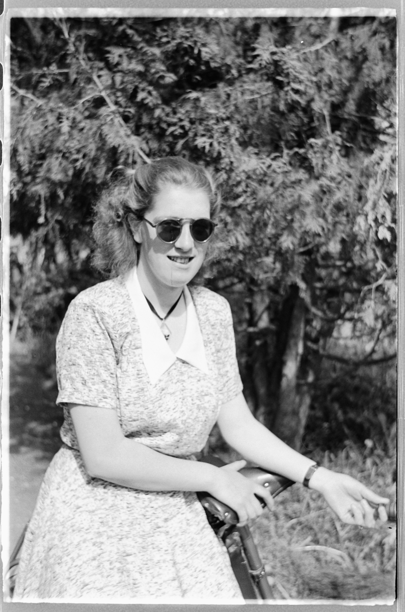 Håkon Prestkværn, Helga Sjøli, gift Engelstad, Moelv. Kvinne med solbriller ved en sykkel.