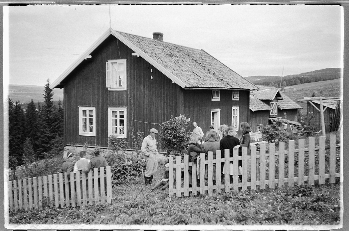 Håkon Prestkværn, Gruppe mennesker samlet i hagen foran et hus med stakittgjerde.