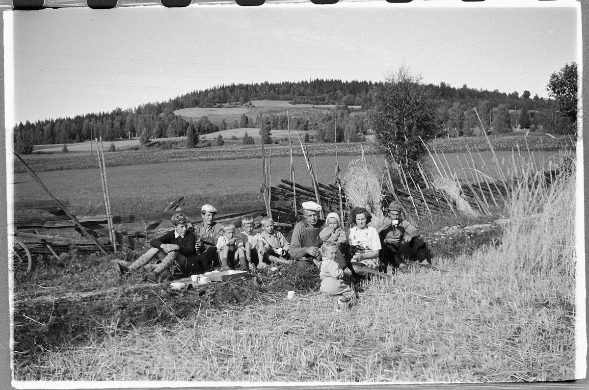 Håkon Prestkværn, Ukjente menn, ei kvinne og flere barn spiser niste på et jorde ved en skigard.