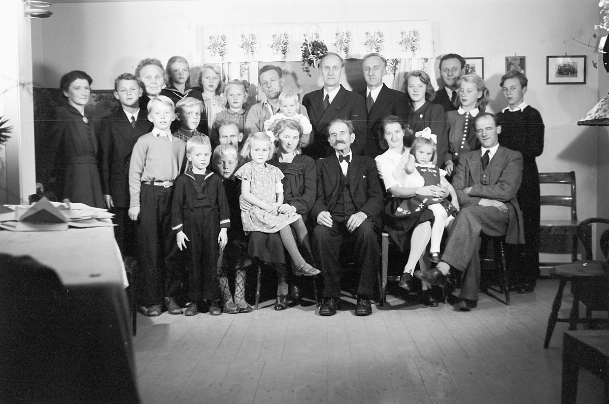 Håkon Prestkværn, Interiør, stue. Stor familiegruppe.