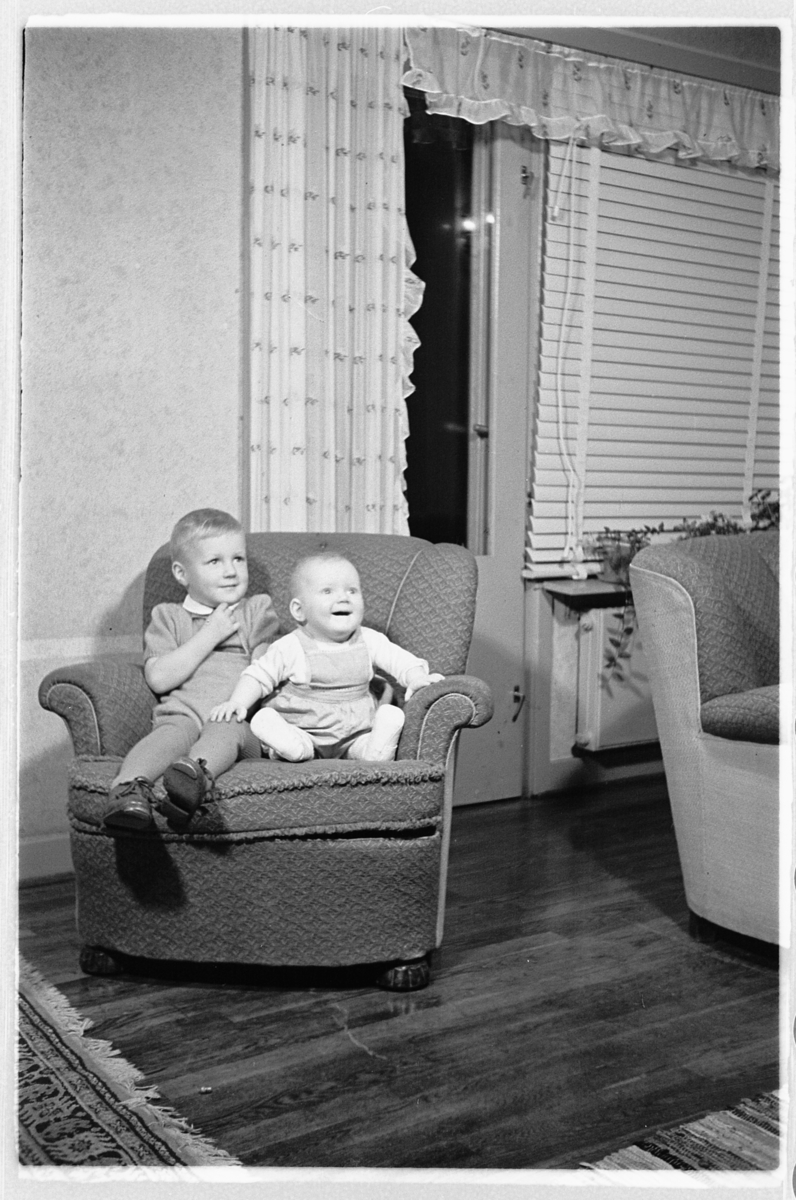 Håkon Prestkværn, Interiør, stue. En gutt og en baby i en stol.