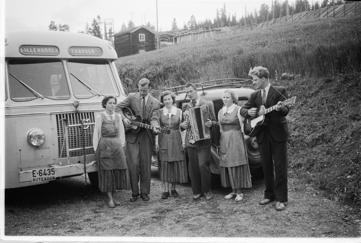 Håkon Prestkværn, Tre menn spiller gitar og trekkspill, mens tre kvinner lytter ved en buss med skilt Lillehammer turvogn. T. h. Ulf Sæhli på gitar. Volvo buss E-6435, Lillehammer Ringsaker Bilruter.