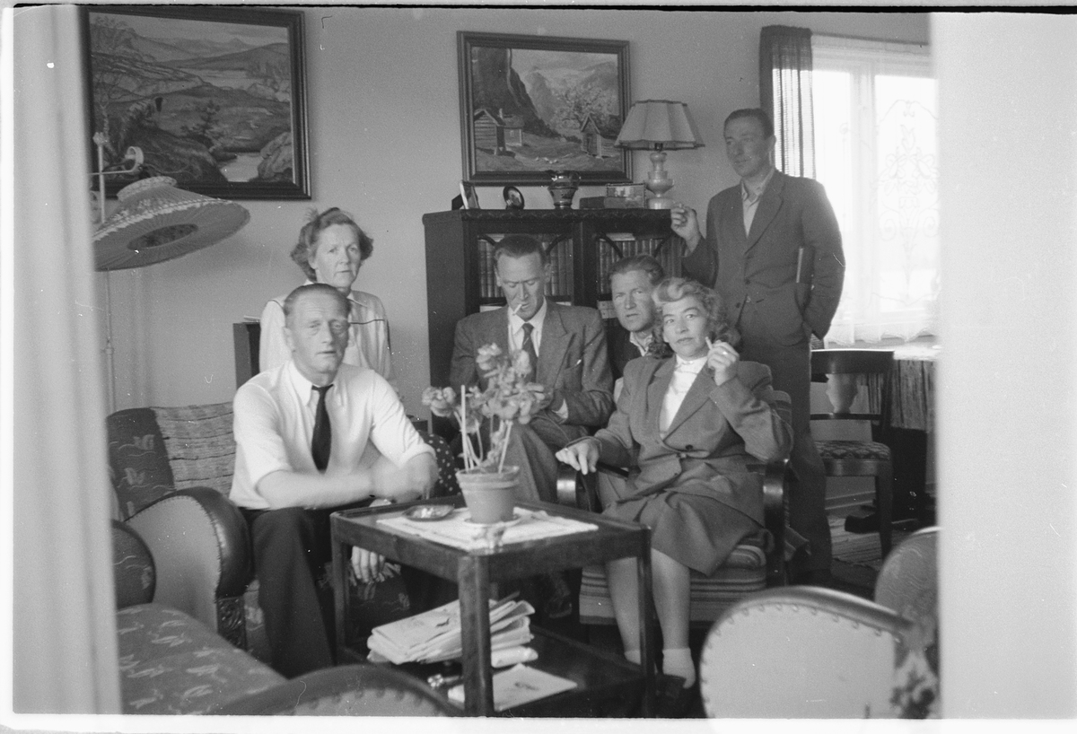 Håkon Prestkværn, Interiør, stue. En gruppe mennesker samlet rundt stuebordet. Fra venstre; Paul Pettersen, Martha (f. Prestkværn) hans kone, Einar Prestkværn, Håkon Prestkværn, ukjent dame (Einars 2. kone). Mann i bakgrunnen ukjent.