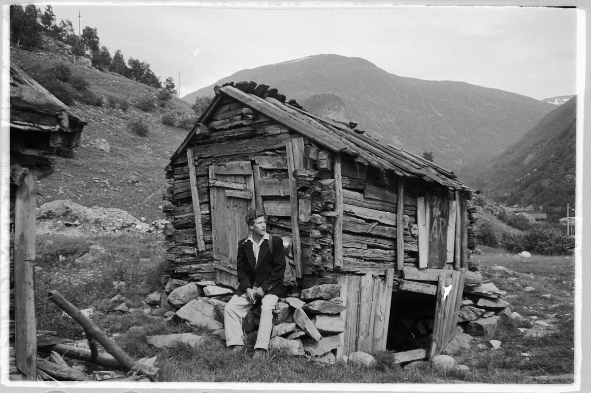 Håkon Prestkværn, Mann sitter ved gammel hytte. I Øvre Årdal, Sogn og Fjordane.